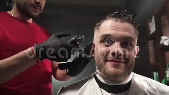 理发店里顾客的脸很滑稽理发师用电剪头理发视频的预览图