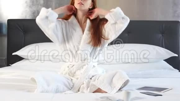 红发女孩穿着白色浴袍躺在酒店房间的床上视频的预览图