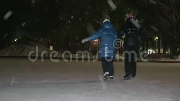 在下雪的时候妈妈和女儿一起在冬季公园的冰场上溜冰母亲和少女视频的预览图