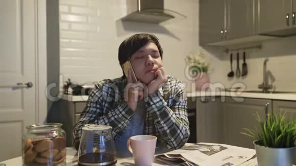 熟睡的亚洲人在家厨房里用手机说话视频的预览图