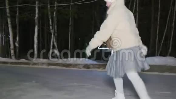 在冬季公园的冰场上训练燕子姿势的少女少女在夜间溜冰场溜冰视频的预览图