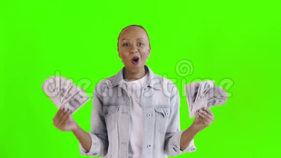 满意的兴奋的兴奋的非裔美国妇女在绿色背景的让夹克上展示金钱和说上帝的上帝视频的预览图