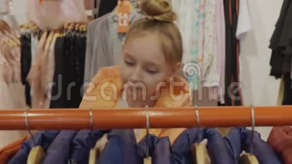 可爱的少女在时尚精品店里看着有时髦衣服的衣架视频的预览图