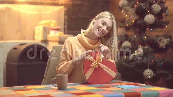 在家中打开圣诞礼物的圣诞年轻女子快乐的女人打开圣诞礼物新年女孩视频的预览图