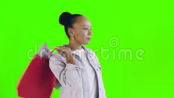 美国黑人妇女带着购物袋的肖像正在工作室的绿色背景上喝咖啡琼夹夹克视频的预览图