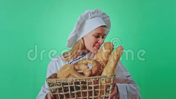 漂亮的女面包师闻着爱情的味道新鲜的面包在绿色工作室里的镜头前的篮子里起泡视频的预览图