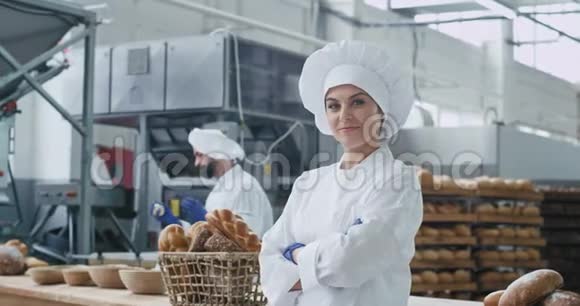美丽的女人面包师在镜头前笑得很漂亮背景是大面包店业和面包师男子移动得很有趣视频的预览图