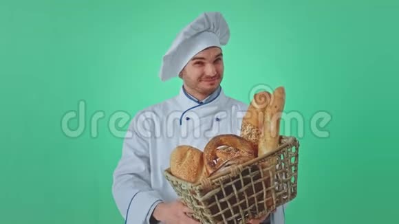 绿墙画室的面包师一个笑容满面的男人手里拿着一个带着新鲜面包的篮子他直视着摄像机视频的预览图