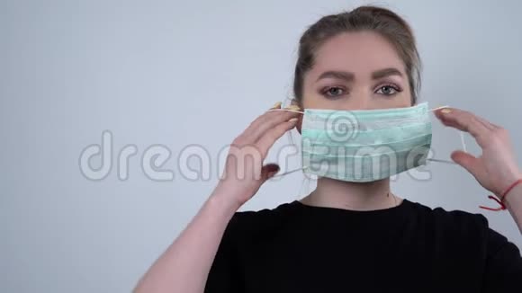 女人戴着面具看着白色背景上的相机欧洲年轻女性的大流行画像视频的预览图