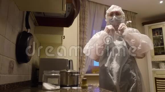 穿着防护服在厨房做饭的女人视频的预览图