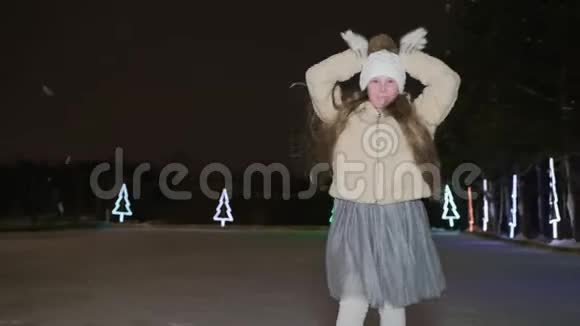 冬天公园的冰场上跳舞的快乐女孩跳舞的女孩少年在溜冰场晚上溜冰冬季青少年视频的预览图