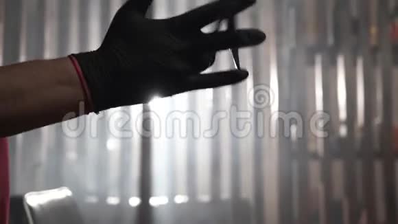 职业理发师戴着黑色手套双手在雾中光线的背景下扭动剪刀视频的预览图