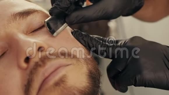 在男式沙龙里用直剃须刀把剃须刀的胡子男人靠近理发店将剃须刀刮至男性刚毛视频的预览图