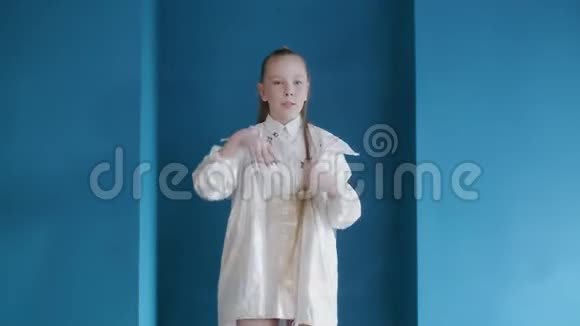 漂亮的穿着白色衣服的少女在蓝色背景上跳舞快乐雀斑的女孩在跳舞视频的预览图