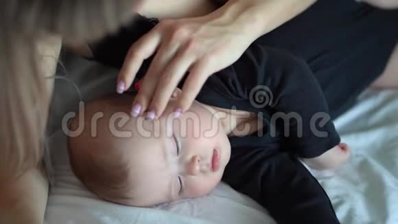 母亲抚摸着熟睡的婴儿的头视频的预览图