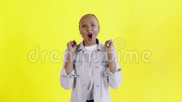 美丽快乐的非洲年轻女子说哦我的上帝在黄色背景的Jean夹克上跳舞视频的预览图