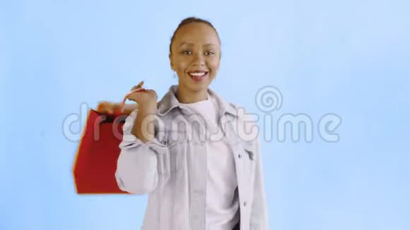 画室蓝色背景上带购物袋的非裔美国妇女肖像快乐的女人在购物视频的预览图