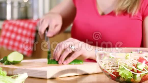 一个年轻女人的手切黄瓜做蔬菜沙拉视频的预览图