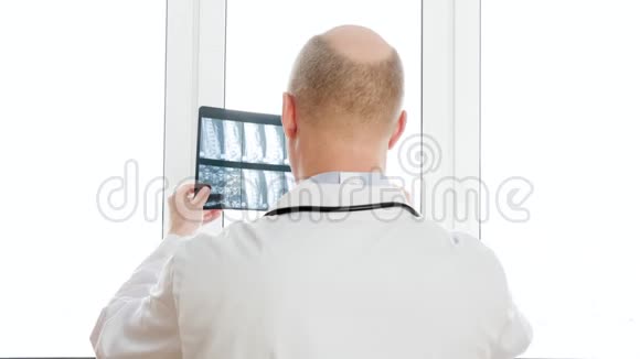 创伤学家在诊所的窗灯背景上看脊椎骨的x射线后景外科医生看背部X视频的预览图