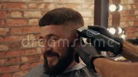 理发店里理发师给微笑的男客户修剪头发的裁剪镜头视频的预览图