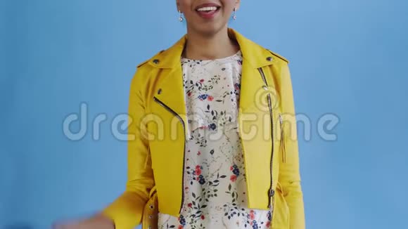 满意的非洲裔美国妇女的钱显示拇指在蓝色背景黄色夹克视频的预览图