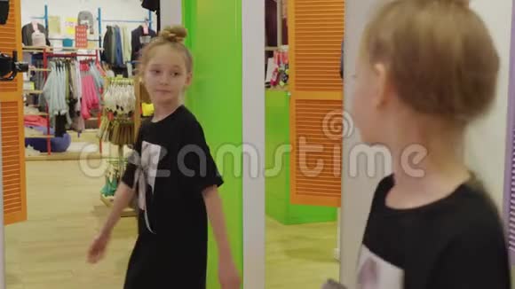 穿着时尚服装在试衣间照镜子的可爱女孩视频的预览图