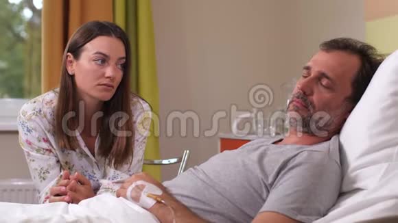 可怜的女人坐在病夫的床边视频的预览图