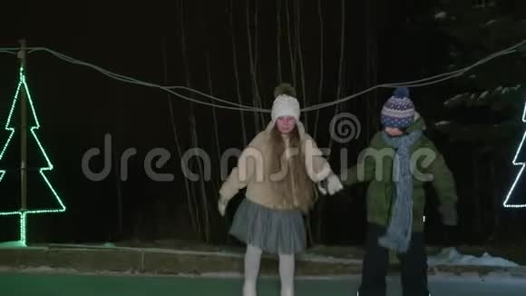 快乐的孩子们在冬天的黑暗中牵手滑冰视频的预览图