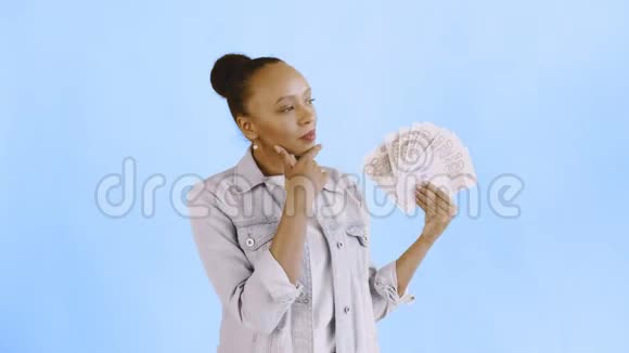 体贴成功的非裔美国女人带着蓝色背景的钱让夹克视频的预览图
