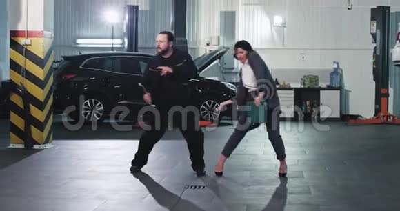 汽车服务中心最好的团队在车库中间跳舞的工人女人和机械师滑稽而兴奋视频的预览图