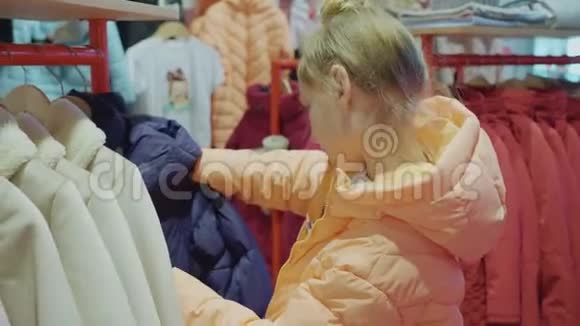 少女在时装陈列室挑选夹克年轻女子在商店里看衣服少女购物视频的预览图