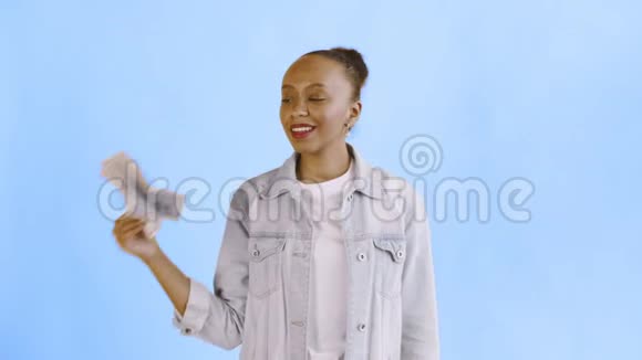 满意的非洲裔美国妇女的钱显示拇指在蓝色背景让夹克视频的预览图