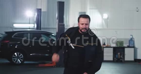 有魅力的成熟机械师在修好汽车后在镜头前跳舞和动作滑稽视频的预览图