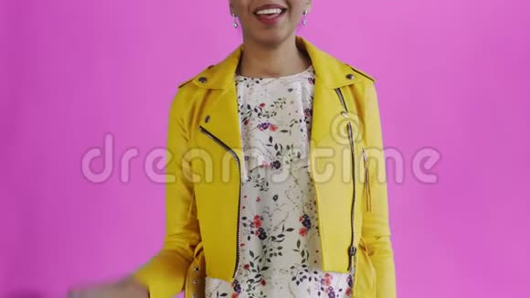 满意的非洲裔美国妇女的钱显示拇指在粉红色背景黄色夹克视频的预览图