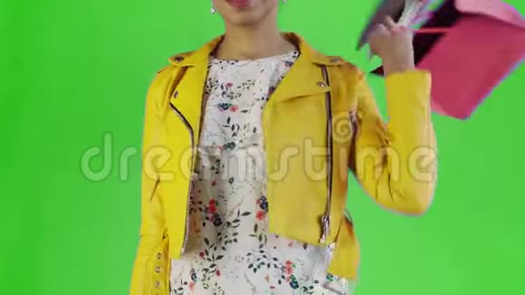 美国黑人妇女的肖像与购物袋和手机绿色背景在工作室黄色夹克视频的预览图