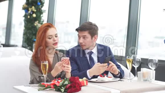 年轻的欧洲夫妇在餐馆约会红发女孩在他的智能手机上显示一个男人的照片视频的预览图