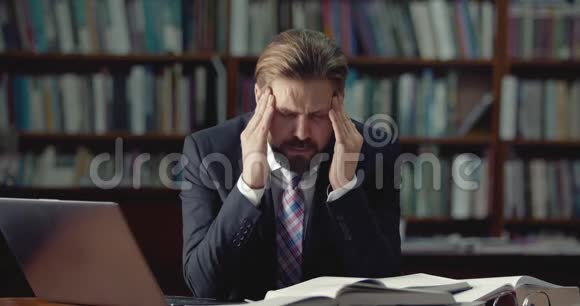 图书馆里有笔记本电脑的精疲力竭的男性视频的预览图