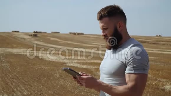 蓄胡子的农夫手里拿着一块平板电脑放在干草捆上视频的预览图