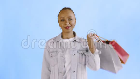 非洲裔美国妇女的肖像与购物袋和金钱风扇的蓝色背景在工作室珍妮夹克视频的预览图