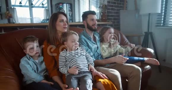 家庭幸福的肖像年轻微笑的白种人爸爸妈妈和孩子们一起看电视玩得很开心视频的预览图