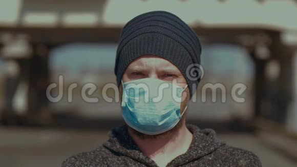 一个人站在户外戴着医疗面罩看着相机以防止流感或冠状病毒日冕视频的预览图