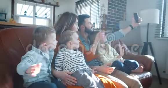 快乐的年轻的欧洲家庭有三个孩子在智能手机视频通话时向朋友挥手在家里慢动作视频的预览图