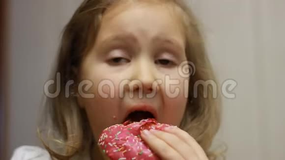 小孩嘴咬玫瑰甜甜圈特写小女孩吃甜甜圈加糖好吃的甜的甜的视频的预览图