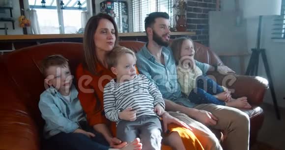 快乐的家庭娱乐时间在一起年轻的白种人妈妈爸爸和三个可爱的孩子放松在家看电影慢动作视频的预览图