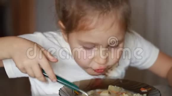孩子用勺子汤吃饭午餐结束了一个小女孩坐在家里做饭和吃食物的桌子上的肖像视频的预览图