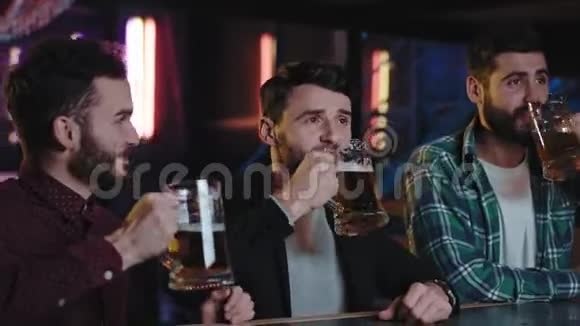 老朋友长得漂亮的家伙在酒吧里开会喝啤酒在电视上看他们最喜欢的游戏他们太兴奋了视频的预览图