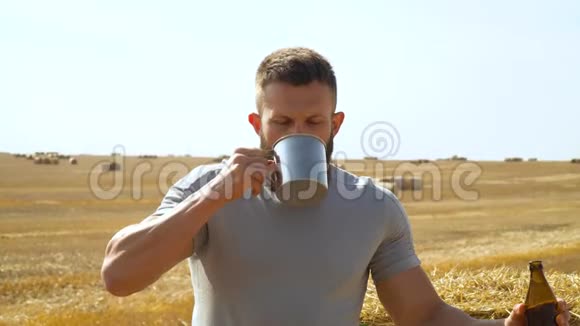 一个人在麦田里喝着金属玻璃和捆新鲜啤酒太阳能热饮视频的预览图