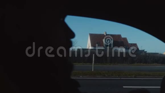 特写剪影的年轻男车司机脸沿小秋晨斯堪的纳维亚小镇道路慢动作视频的预览图