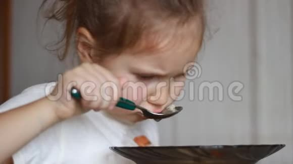 孩子用勺子汤吃饭午餐结束了一个小女孩坐在家里做饭和吃食物的桌子上的肖像视频的预览图