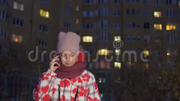 可爱的少女在户外散步晚上用智能手机聊天视频的预览图